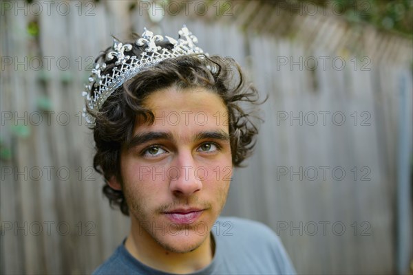 Hispanic man wearing crown in backyard