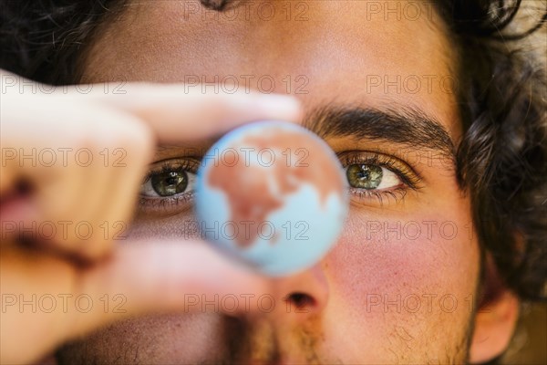 Close up of Hispanic man holding miniature globe