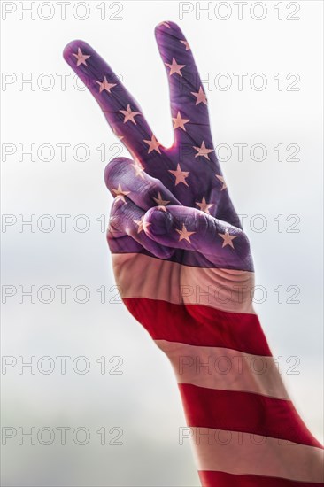 Hand of Caucasian man with American flag gesturing peace