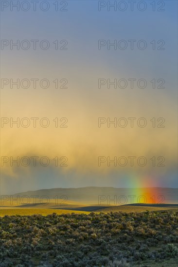 Rainbow and clouds over desert landscape