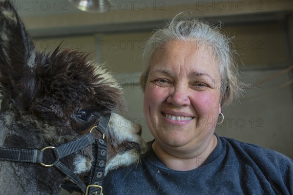 Caucasian farmer smiling with alpaca