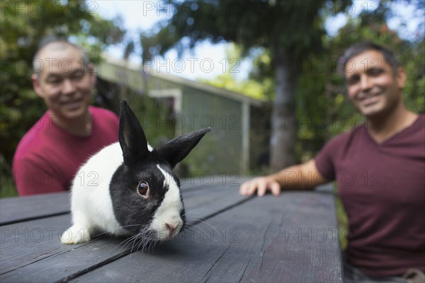 Mixed race men with rabbit on picnic table