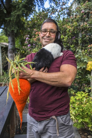 Mixed race man carrying rabbit and knitted carrot