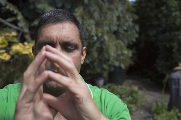 Mixed race man concentrating with hands clasped