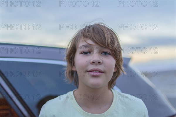 Caucasian teenage boy smiling at car