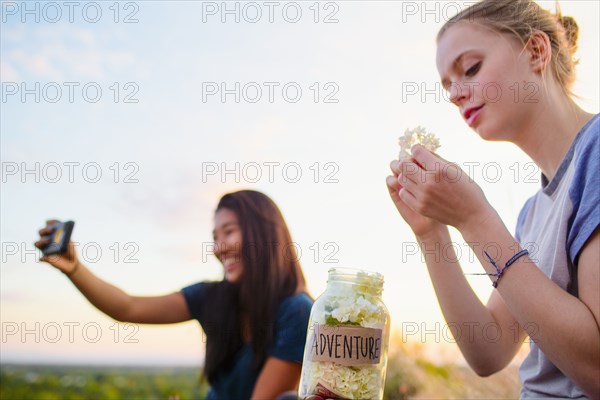Teenage girls photographing and relaxing outdoors