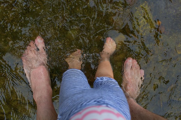 Father and daughter standing barefoot in water
