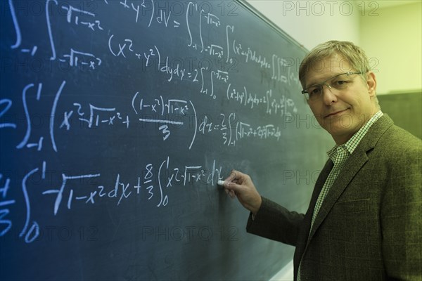 Caucasian teacher writing on chalkboard