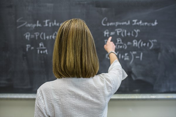 Caucasian teacher pointing to chalkboard