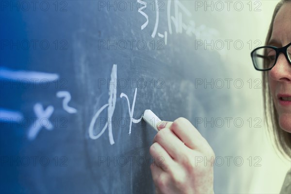 Caucasian teacher writing on chalkboard