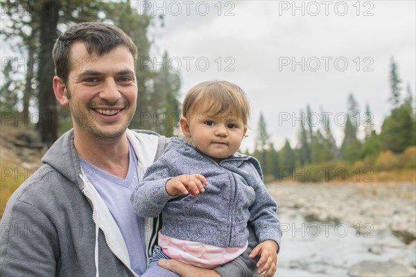 Father carrying daughter at river