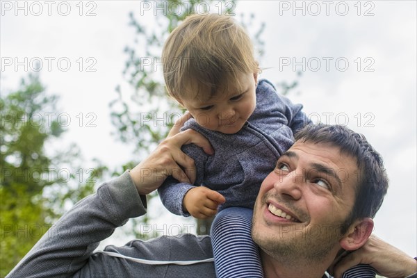 Father carrying daughter on shoulders outdoors