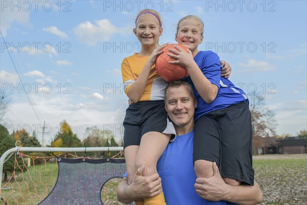 Caucasian father holding daughters in field