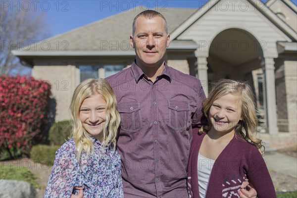 Caucasian father and daughters smiling in yard