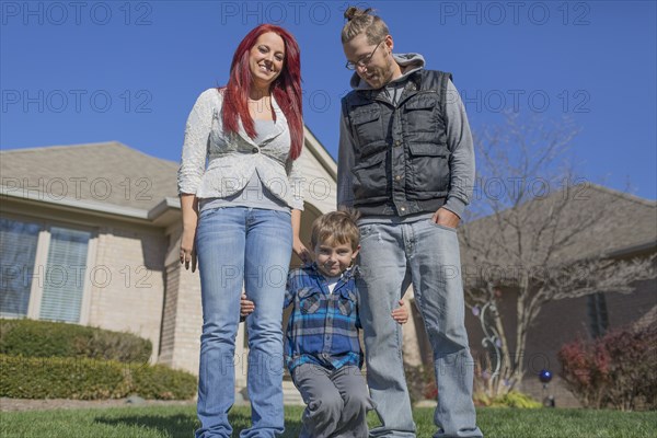 Caucasian parents and son smiling in yard