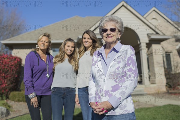 Caucasian multi-generation family smiling in yard