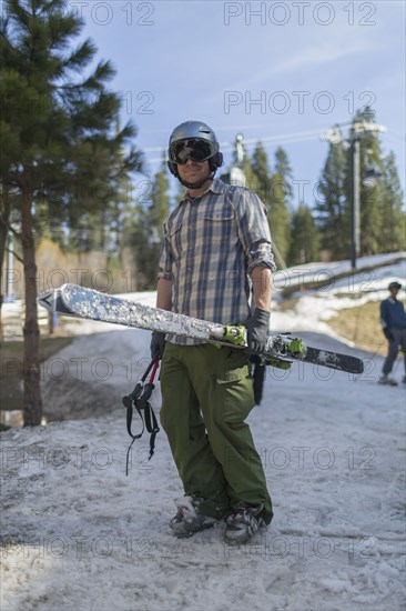 Caucasian man holding skis on snowy hillside