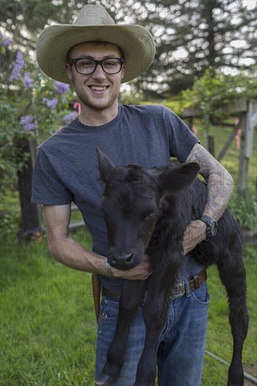 Caucasian farmer carrying calf