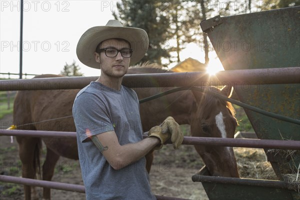 Caucasian farmer leaning on railing near horse