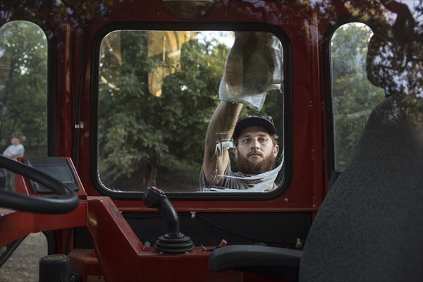 Caucasian man washing window of tractor