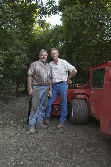 Caucasian men posing near tractor