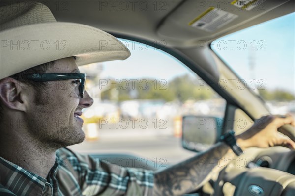 Caucasian man wearing cowboy hat driving car