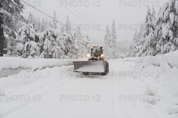 Tractor with snow plow driving on remote road