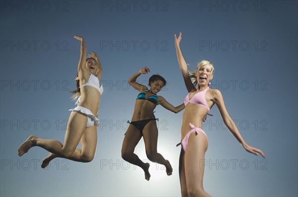 Multi-ethnic women in bathing suits jumping