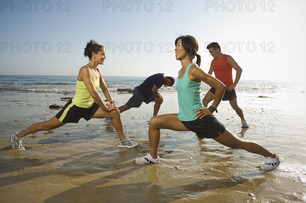 Multi-ethnic runners stretching at beach
