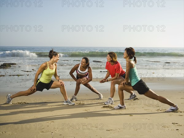 Multi-ethnic runners stretching at beach