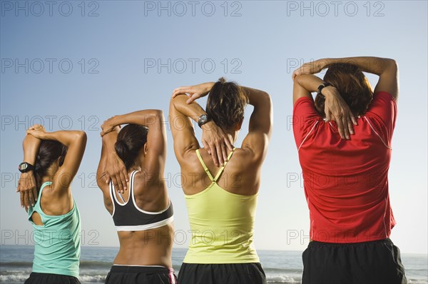 Multi-ethnic female runners stretching at beach