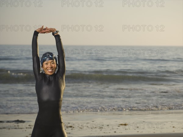 Asian woman stretching in wetsuit and goggles