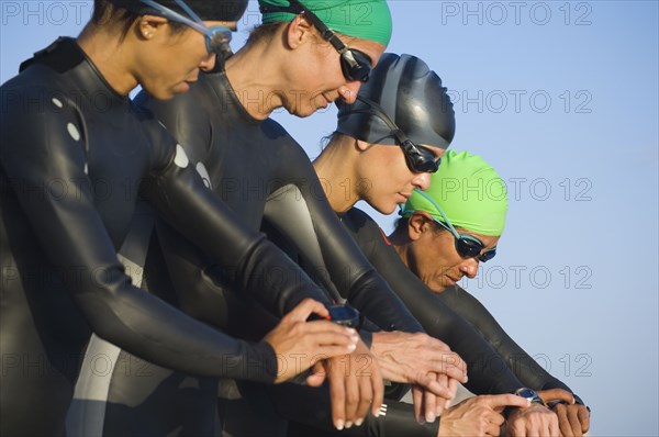 Multi-ethnic swimmers checking watches