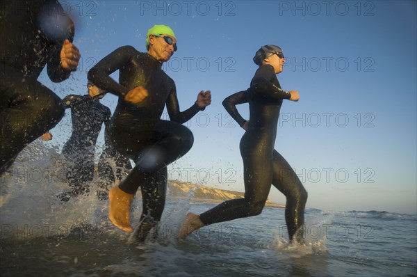 Multi-ethnic swimmers running in surf