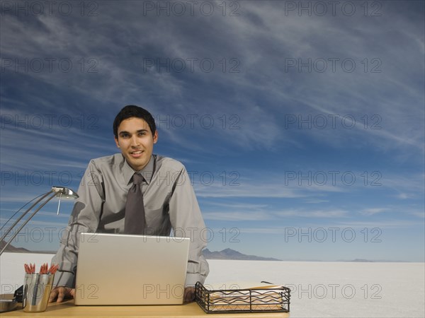 Hispanic businessman at desk on salt flats