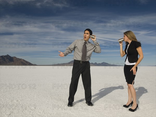 Hispanic businesspeople talking on can and string telephone