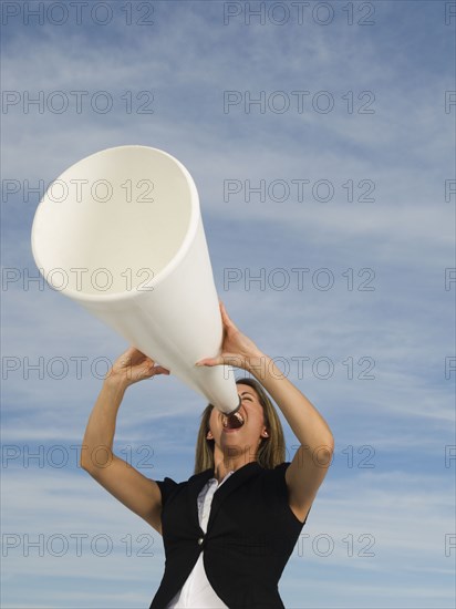 Hispanic businesswoman yelling into megaphone