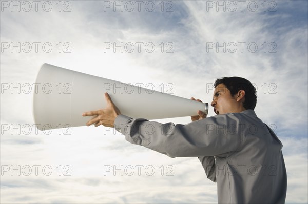 Hispanic businessman yelling into megaphone