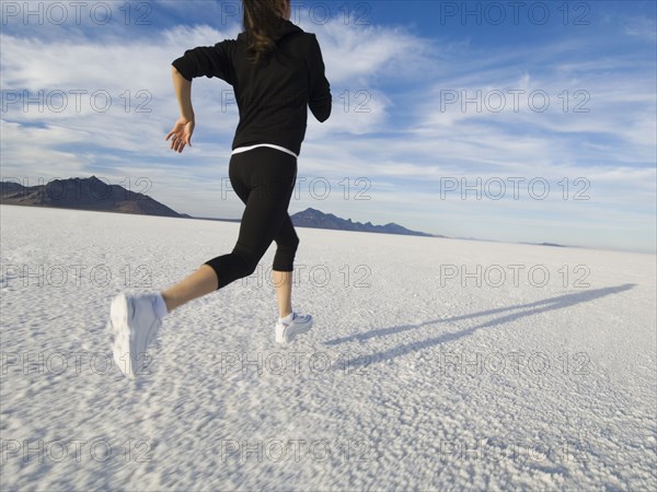 Hispanic woman jogging on salt flats