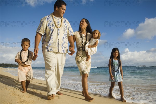 Pacific Islander family walking on beach