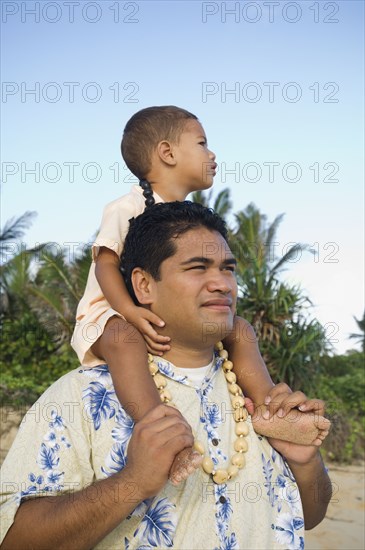 Pacific Islander father with son on shoulders at beach