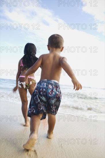 Pacific Islander siblings running on beach