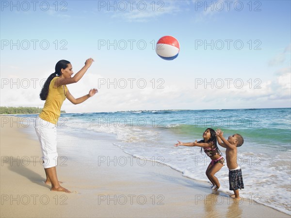 Pacific Islander mother and children playing with beach ball