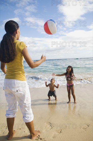 Pacific Islander mother and children playing with beach ball