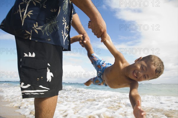 Pacific Islander father and son playing at beach