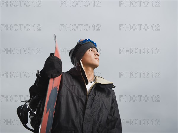 Mixed race teenager standing with snowboard