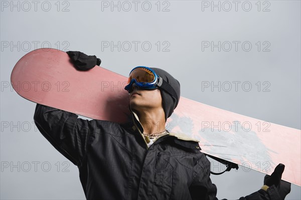 Mixed race teenager standing with snowboard