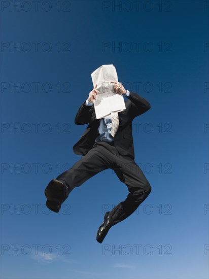 African businessman reading newspaper in mid-air