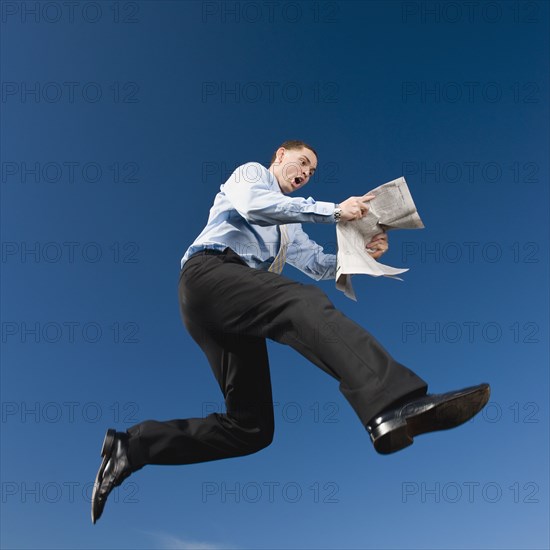 African businessman reading newspaper in mid-air