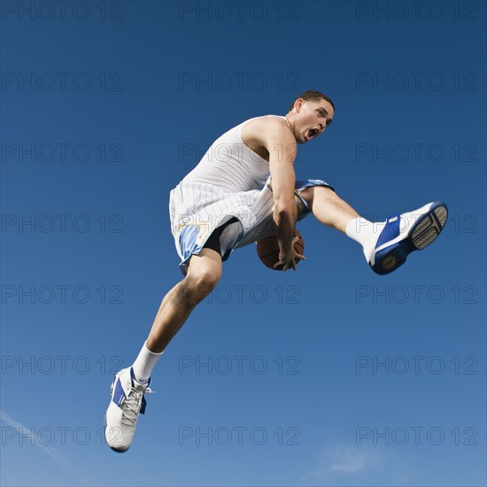 African man playing basketball in mid-air